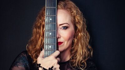 De hals van een gitaar over het oog van een dame heen