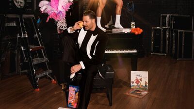 Influencer en stylist Fred van Leer op een krukje voor een piano met veel glitter en glamour om zich heen