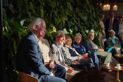 Een groep vrienden die in de tuinkamer zitten luisteren