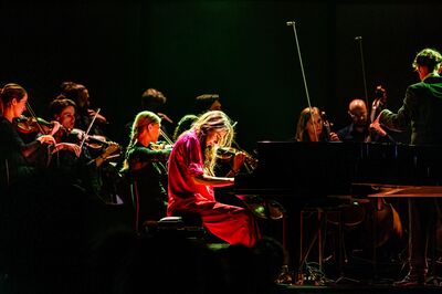 Pianiste met spot op haar tussen een orkest