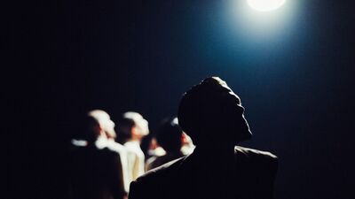 Eén danser met drie dansers op de achtergrond in silhouet met veel tegenlicht