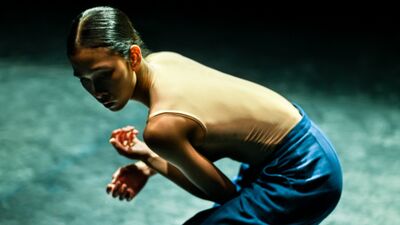 Danseres in elkaar gedoken, hurkend op een podium