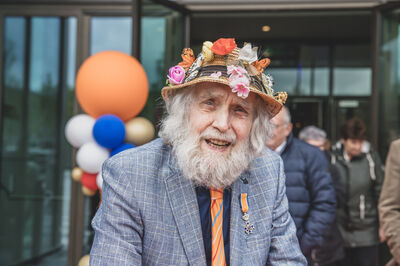 bezoeker met hoed met bloemen en oranje ballon