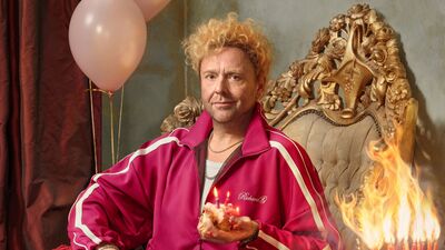 Cabaretier in een stoel met taart en ballonnen