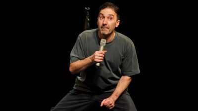 Cabaretier met een microfoon in zijn hand en tongetje uit zijn mond