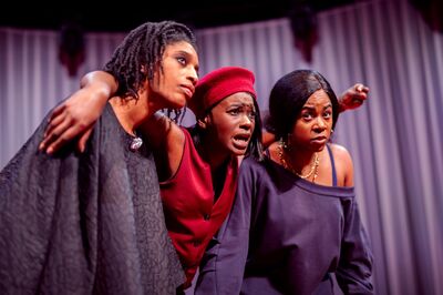 Drie acteurs in kostuums staan dicht bij elkaar op het podium en tonen emotie tijdens een toneelstuk.