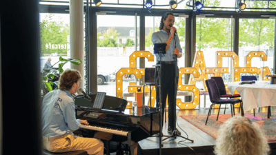 Beer van Tilburg aan de piano en Melle Lingerak op het podium met microfoon