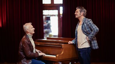Twee heren om een piano zingend en muziek spelend